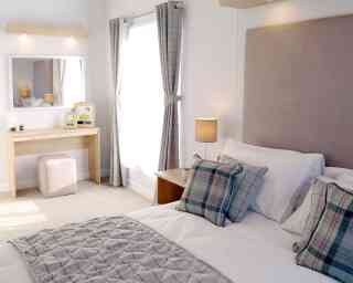 A neatly made bed featuring a white and grey plaid comforter, creating a cosy and inviting atmosphere.