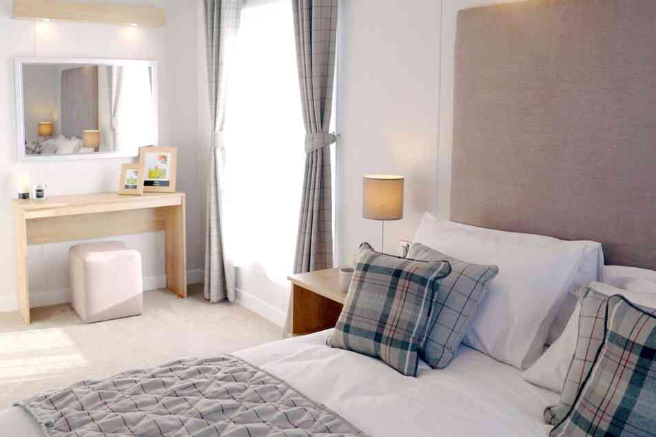 A neatly made bed featuring a white and grey plaid comforter, creating a cosy and inviting atmosphere.