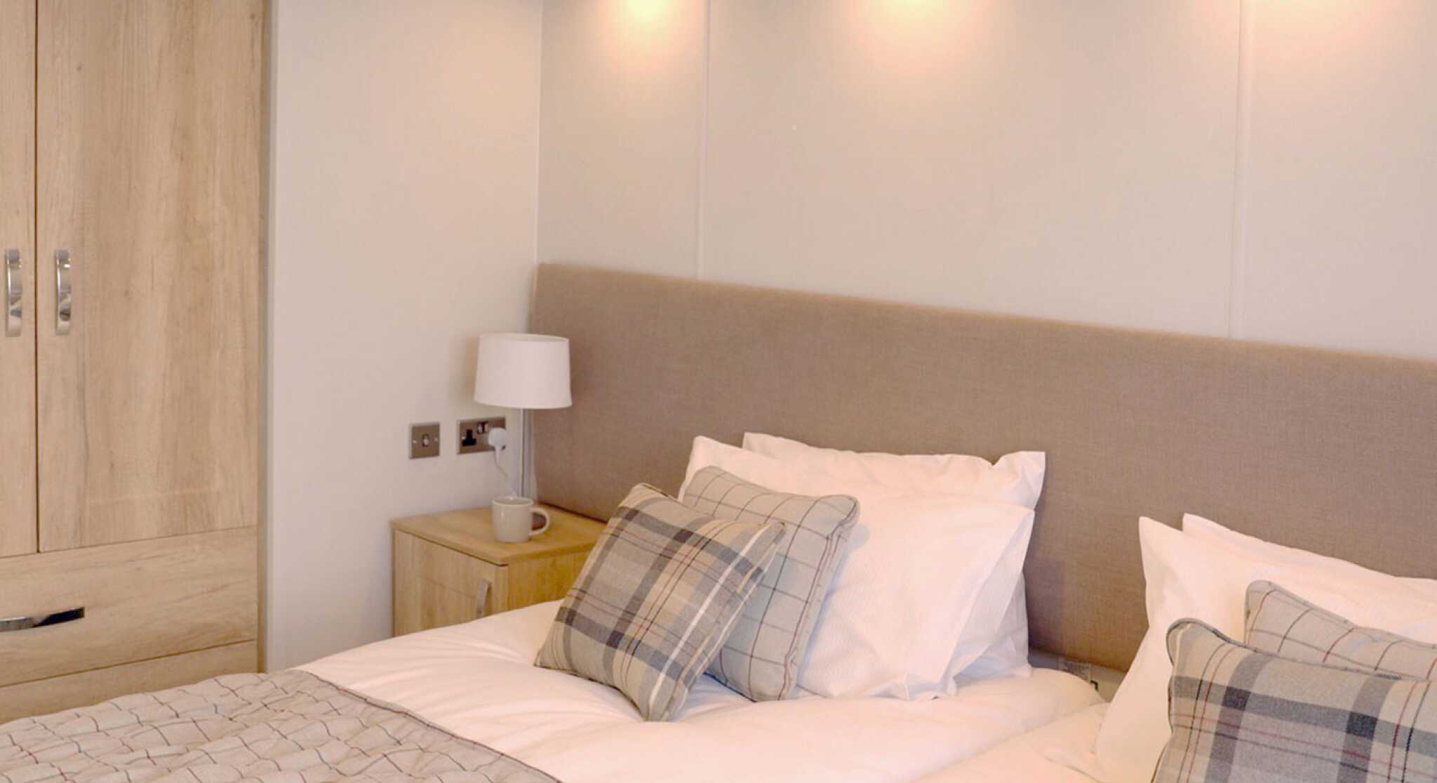 A well-furnished bedroom showcasing two beds and a wardrobe, designed for comfort and practicality.