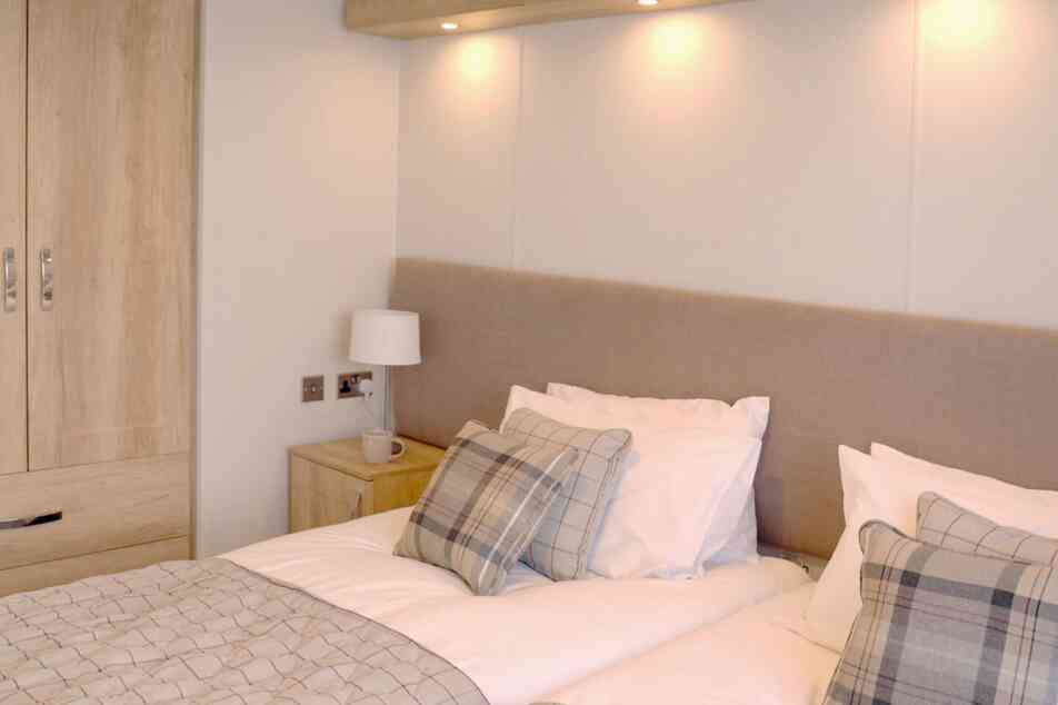 A well-furnished bedroom showcasing two beds and a wardrobe, designed for comfort and practicality.