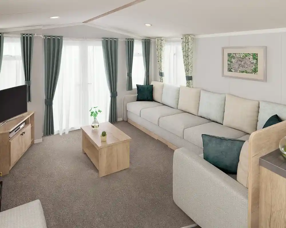A modern living room featuring a spacious grey sectional sofa with light green and teal throw pillows. There is a wooden coffee table in the center and a television on a wooden stand. Natural light streams in through sheer curtains, illuminating the space adorned with leafy patterned drapes.