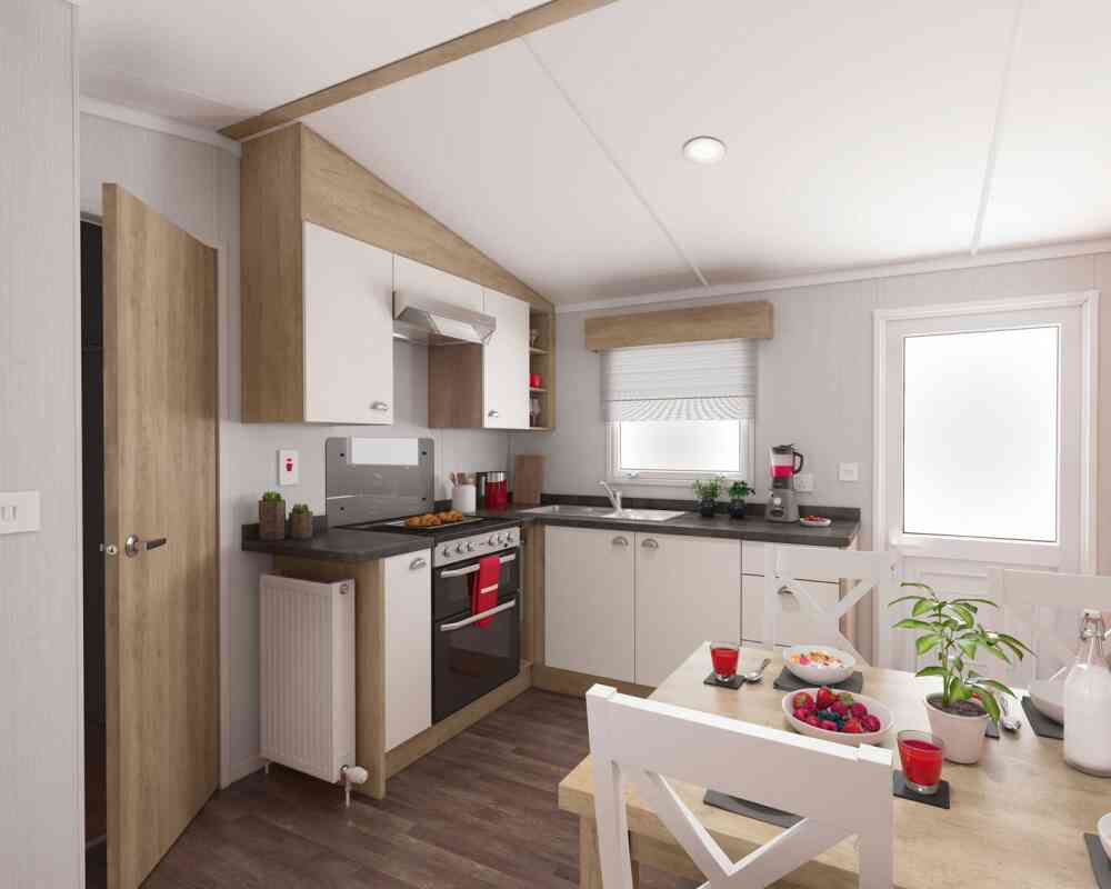 Modern kitchen interior with wooden and white cabinets, stainless steel oven, black countertops, and a cosy dining area decorated with plants and colourful fruit.