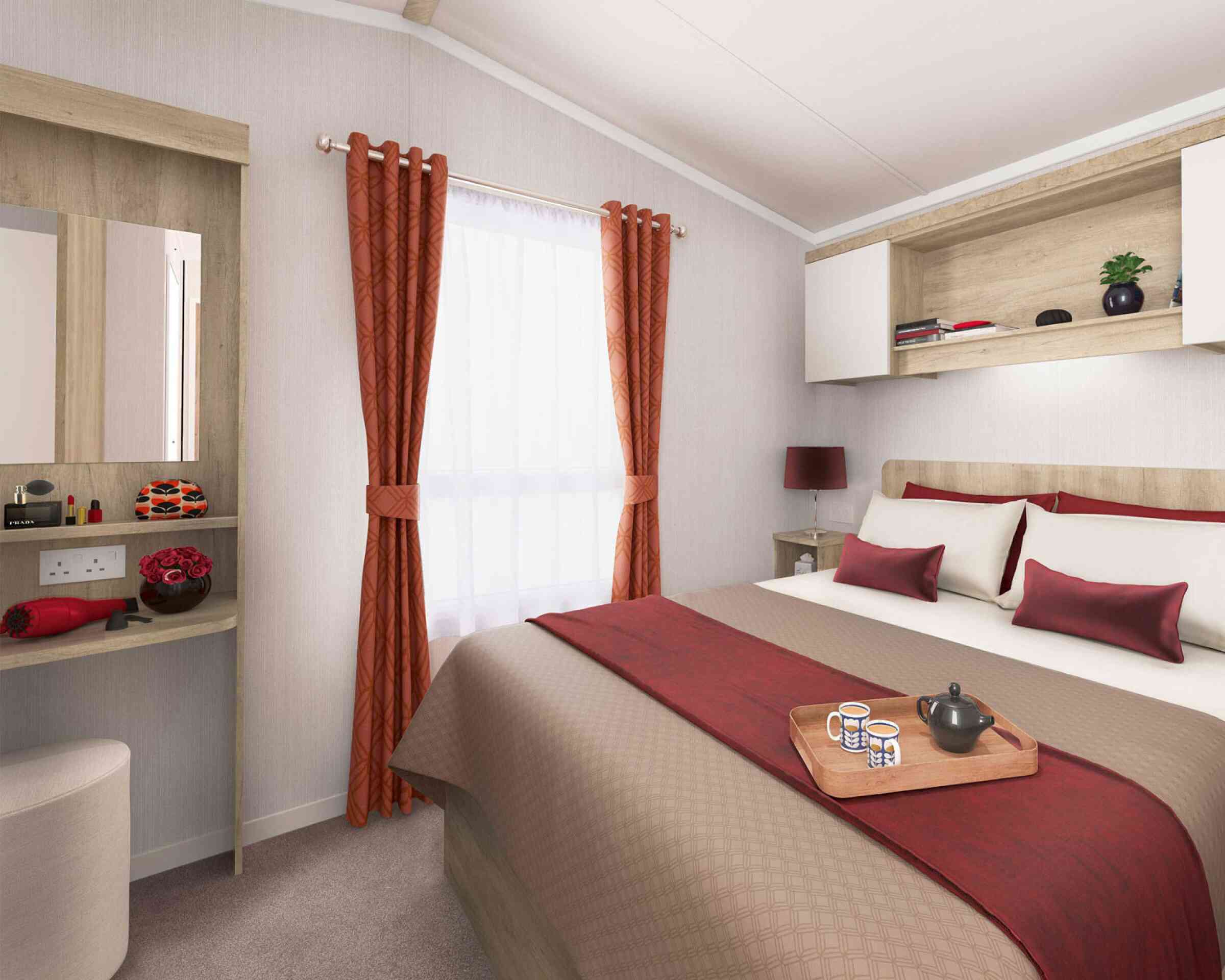 Inviting bedroom featuring a double bed with red and beige linens, a window with red curtains, bedside lighting, and wooden shelving.