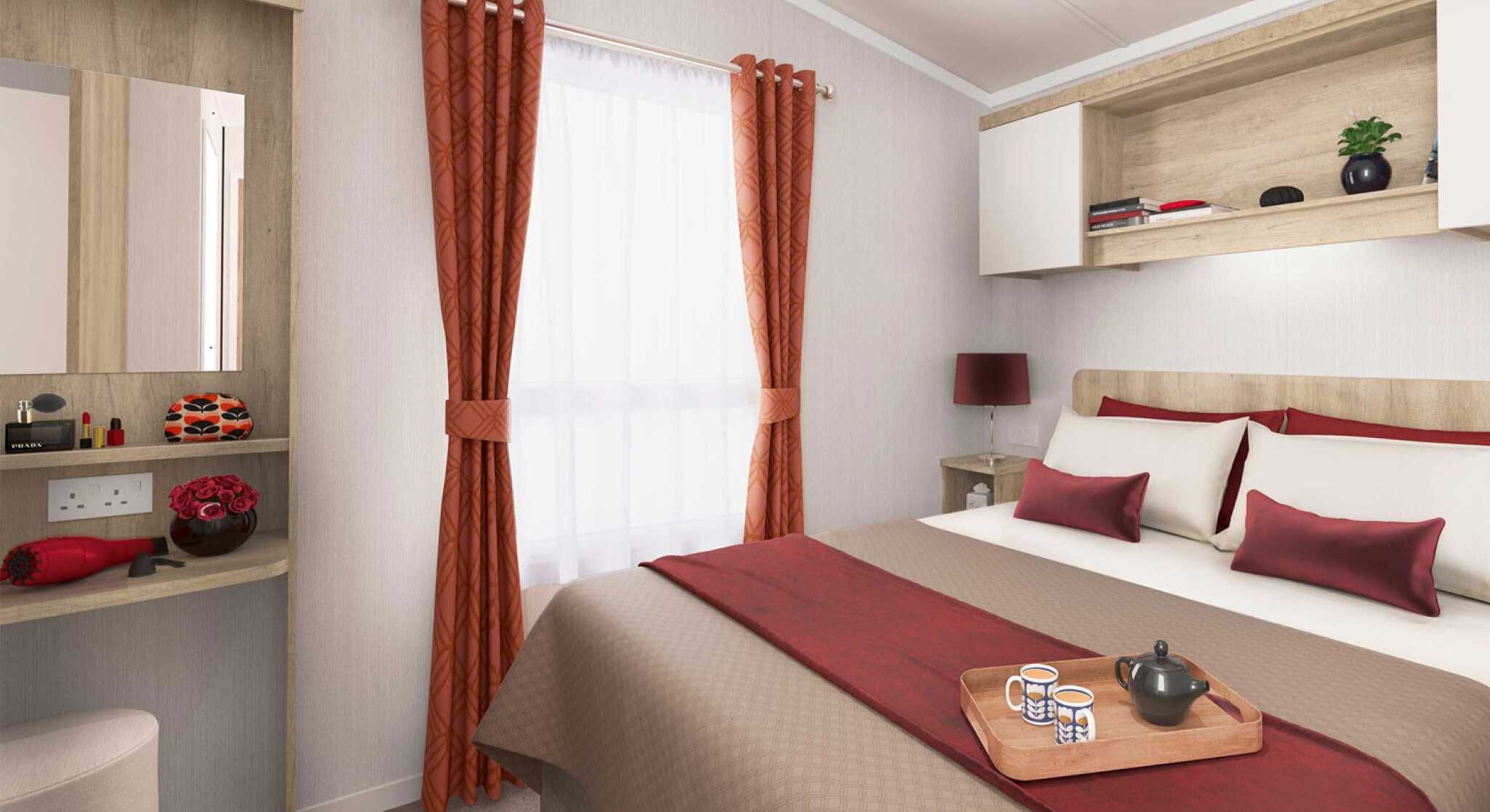Inviting bedroom featuring a double bed with red and beige linens, a window with red curtains, bedside lighting, and wooden shelving.