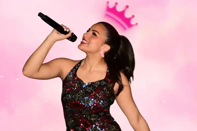 A young woman in a colorful, sequined dress sings joyfully into a microphone. She has a ponytail and is smiling, with a pink crown graphic above her head against a soft pink background.