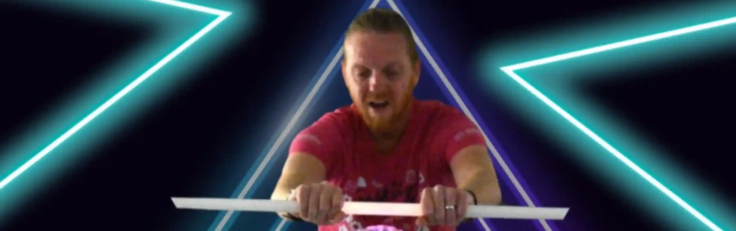 A man in a pink shirt is demonstrating a science experiment involving a clear sphere, surrounded by neon triangular shapes and bright lighting. The text above reads "The Science Dude Presents" and below, "The curious world of."