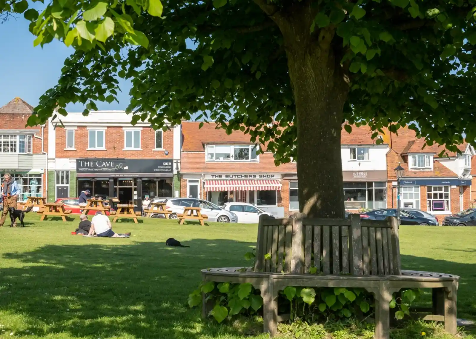 A vintage-style direction signpost with multiple arrows indicating distances to various locations: New Milton (3 miles), Christchurch (9.1 miles), Lymington (3.5 miles), Southampton (2.5 miles), and Keyhaven (1 mile). A thatched roof structure is visible in the background against a clear blue sky.