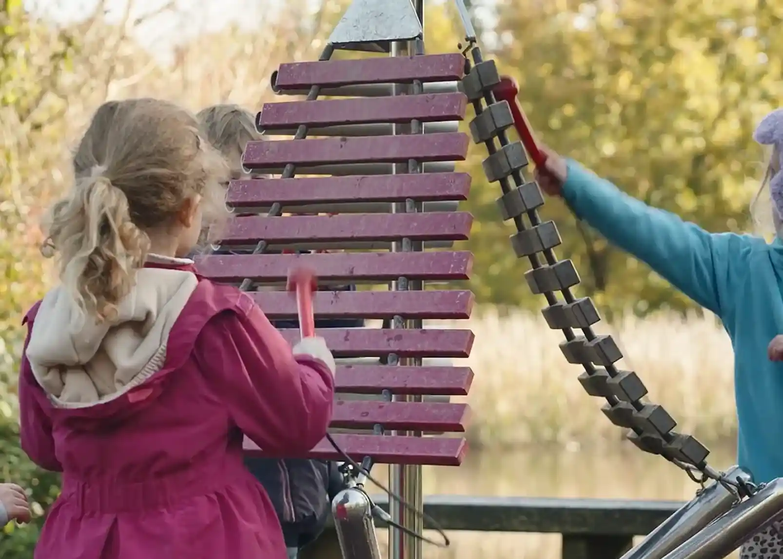 A wooden gazebo nestled among dense green trees in a forested area, surrounded by lush foliage and a gravel pathway.