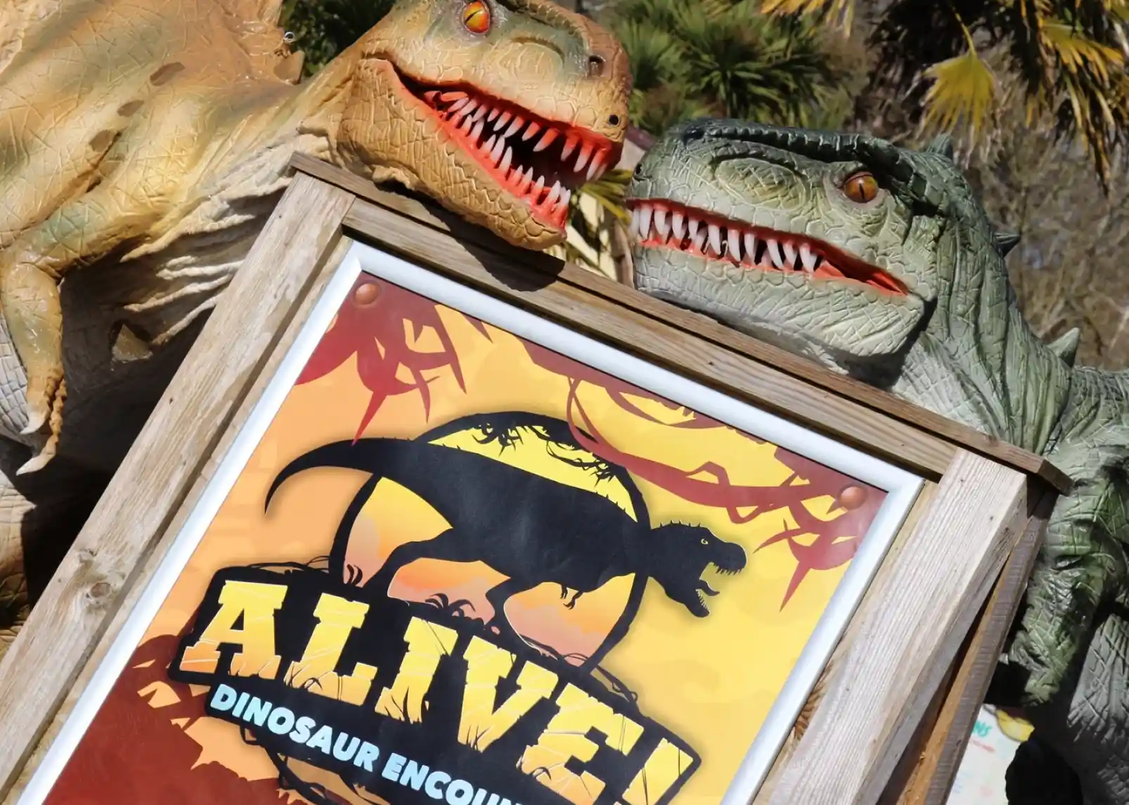 A roller coaster with vintage-style cars zooms through a loop under a clear blue sky. Riders are enjoying the thrill, with some raising their arms in excitement. The track is a bright yellow, contrasting with the surrounding landscape.