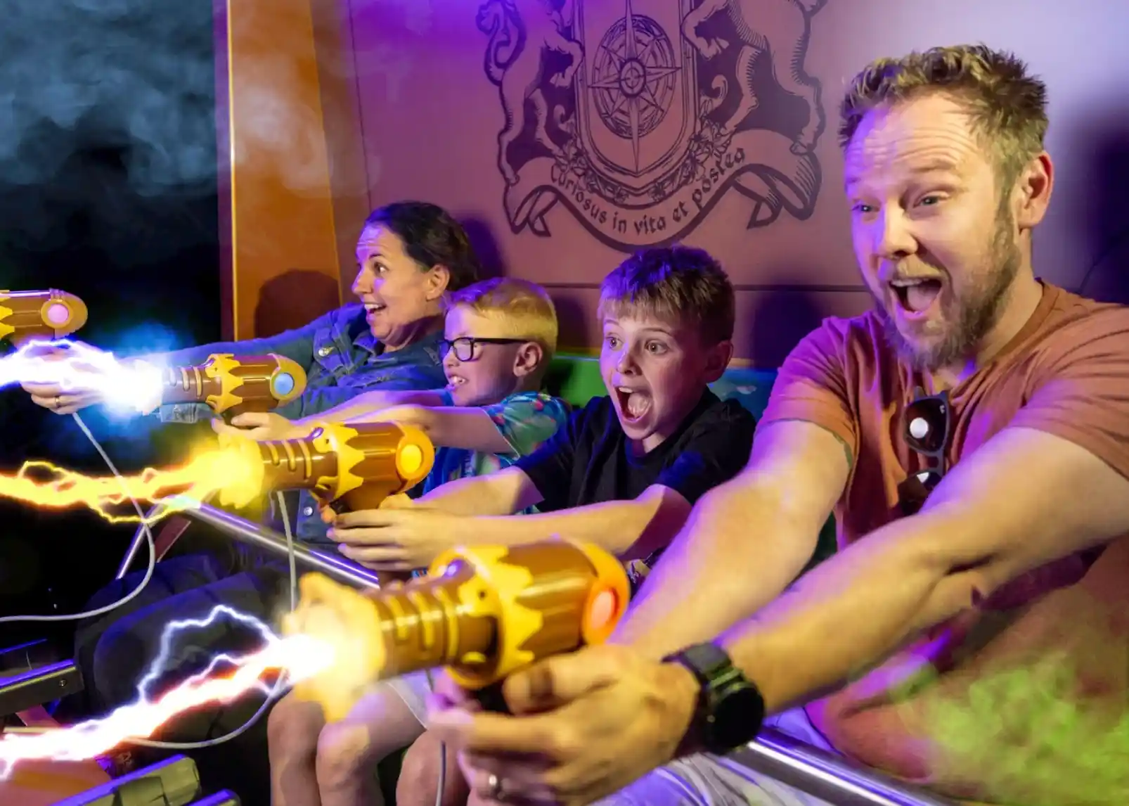 A roller coaster with vintage-style cars zooms through a loop under a clear blue sky. Riders are enjoying the thrill, with some raising their arms in excitement. The track is a bright yellow, contrasting with the surrounding landscape.